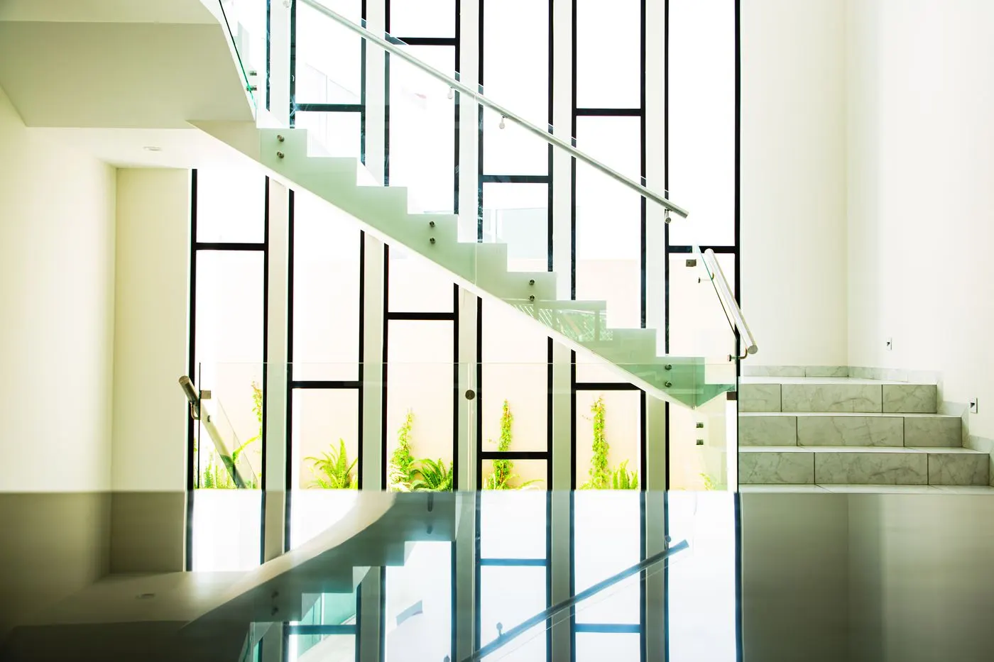 Floating staircase with frameless glass balustrade panels following the stair rake