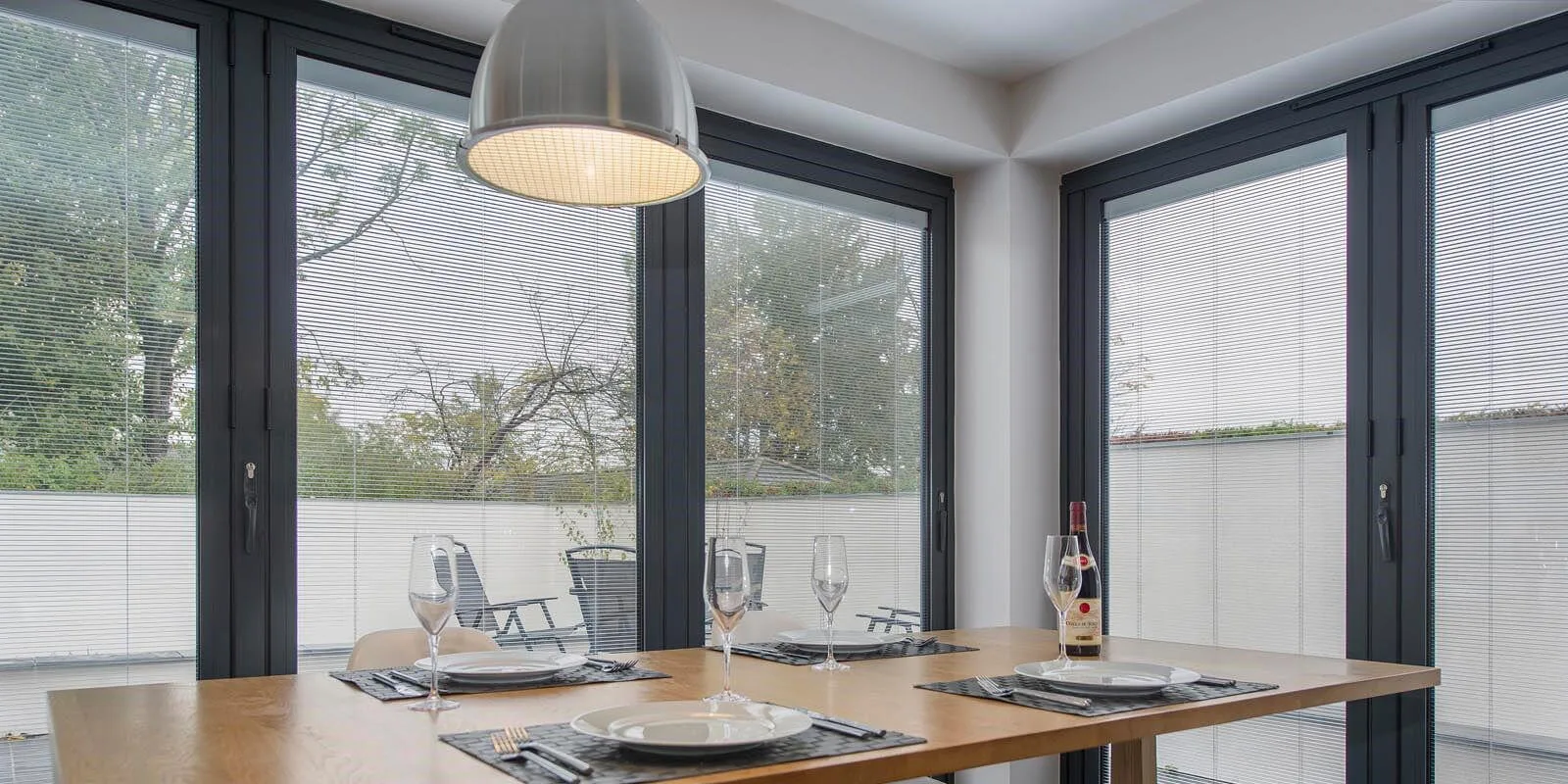 Anthracite bifold doors with silver integral venetian blinds half-lowered inside the sealed glass units