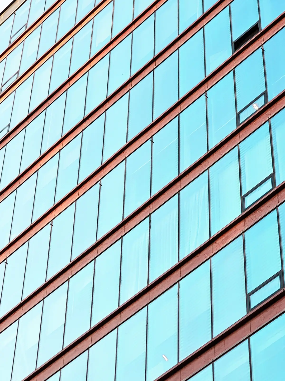Close-up of a blue-tinted reflective solar control glass curtain wall facade