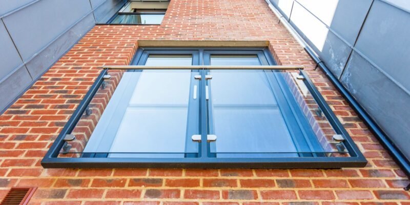Grey glass Juliet balcony on a brick apartment building